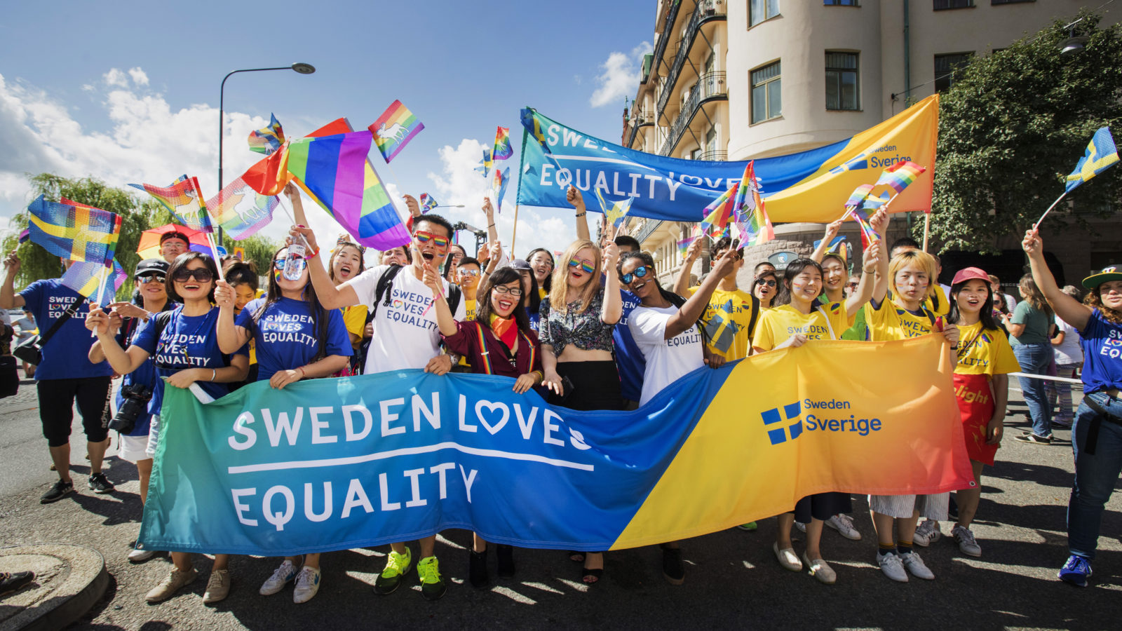 People at a pride parade with a Sweden banner.