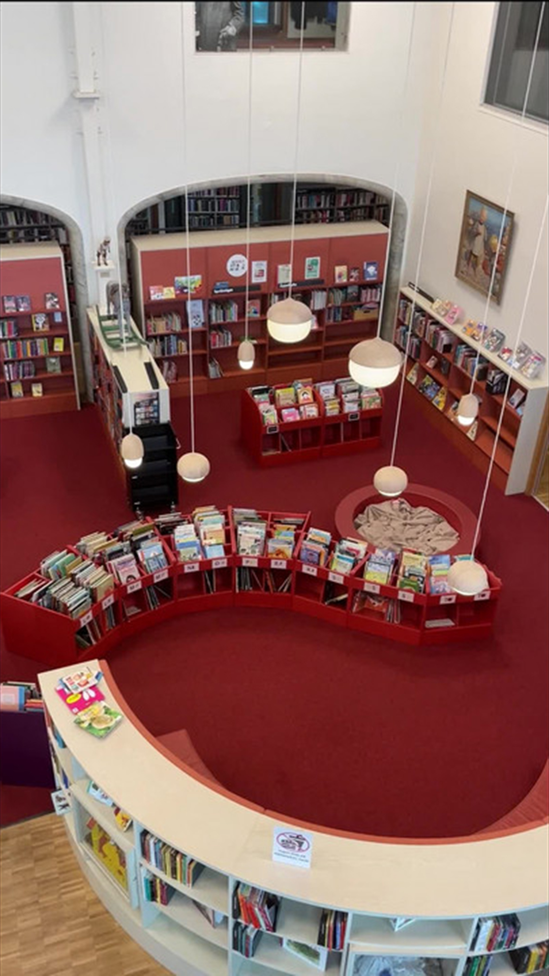 The library from above with a red carpet and white bookshelves.