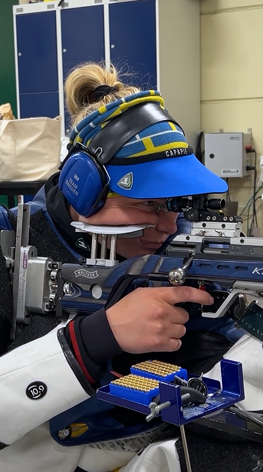 Anna Benson taking shooting, wearing Team Sweden clothing.