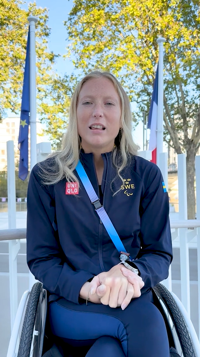 Ebba Einarsson in Paris between an EU flag and a French flag.