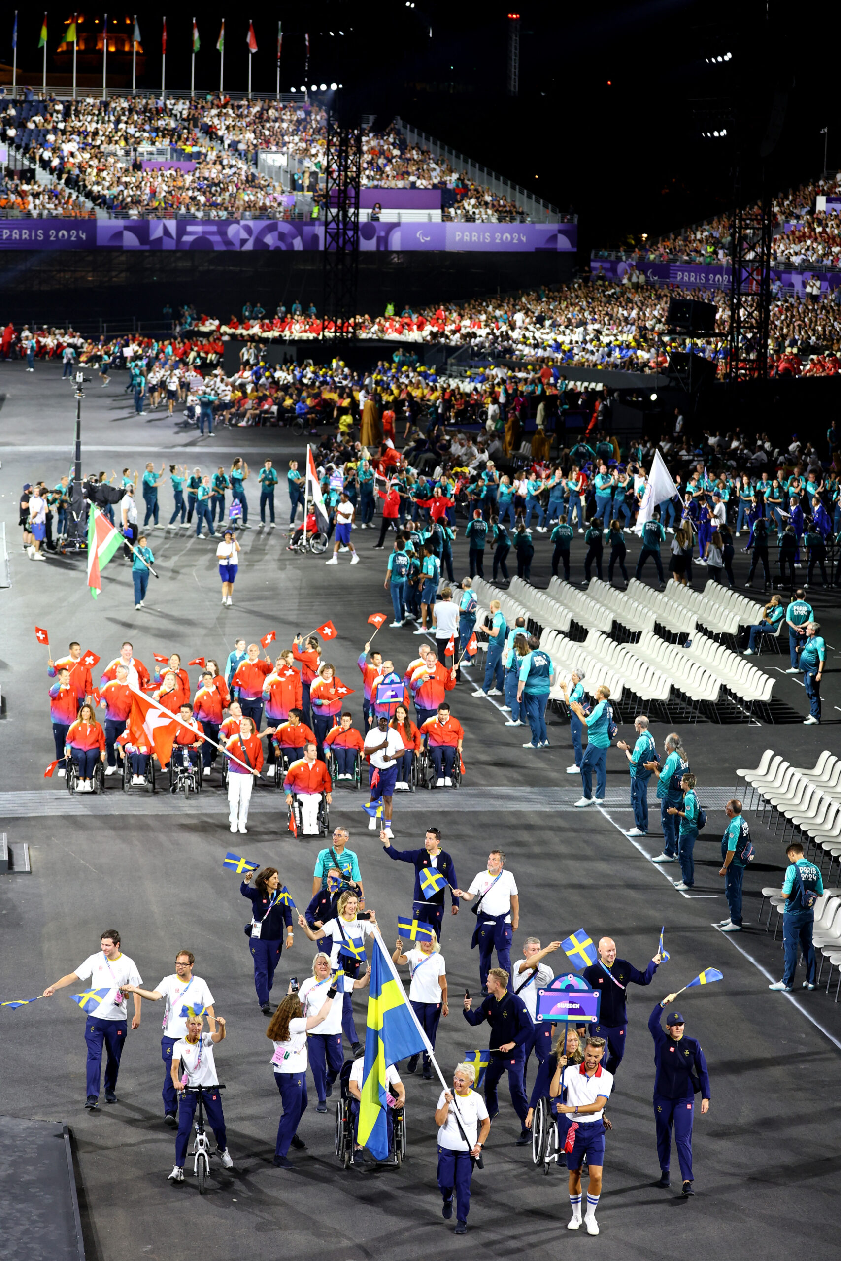 The Swedish troop entering the arena at Paralympics, followed by the Swiss troop.