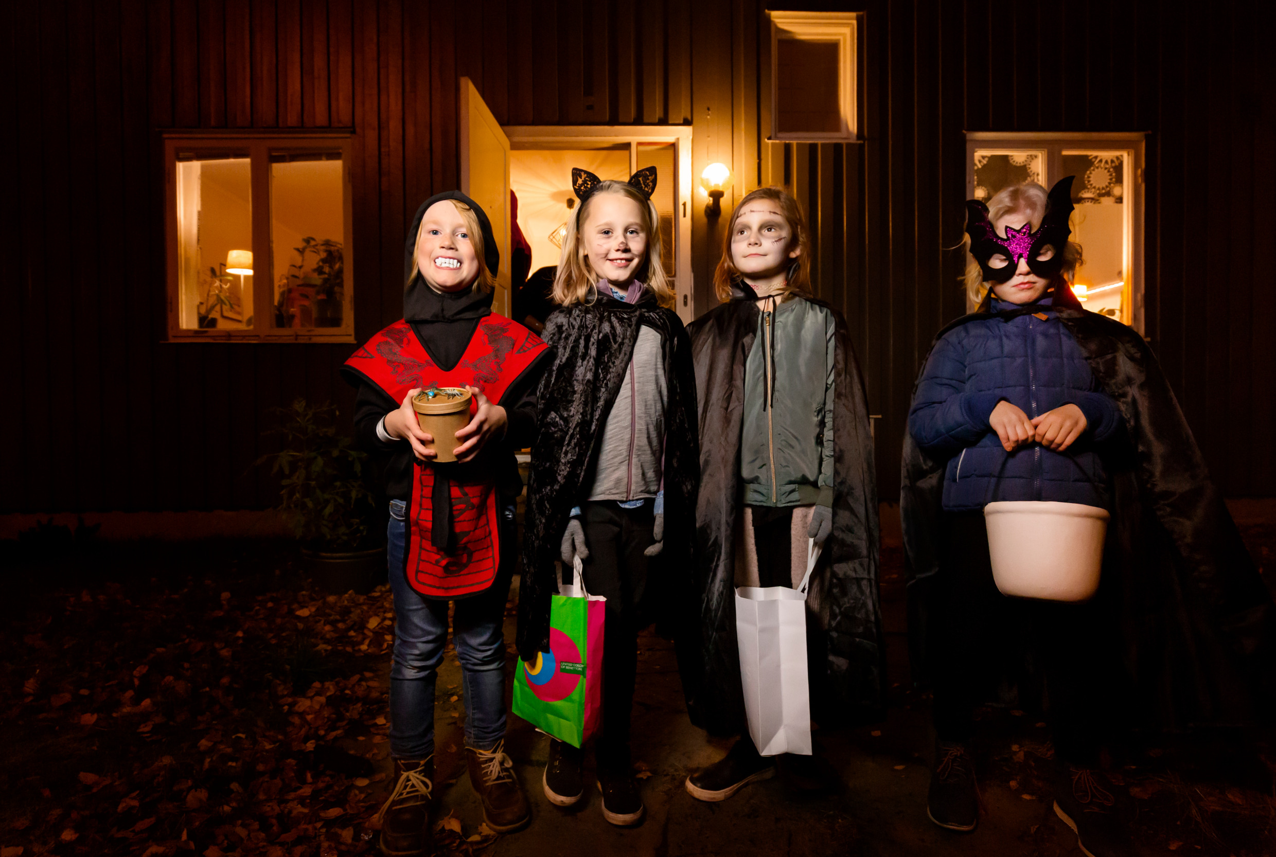 Kids in costumes are standing outside a house.