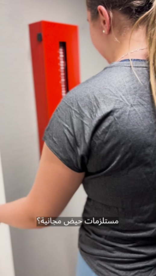 A girl taking free tampons from a red locker.