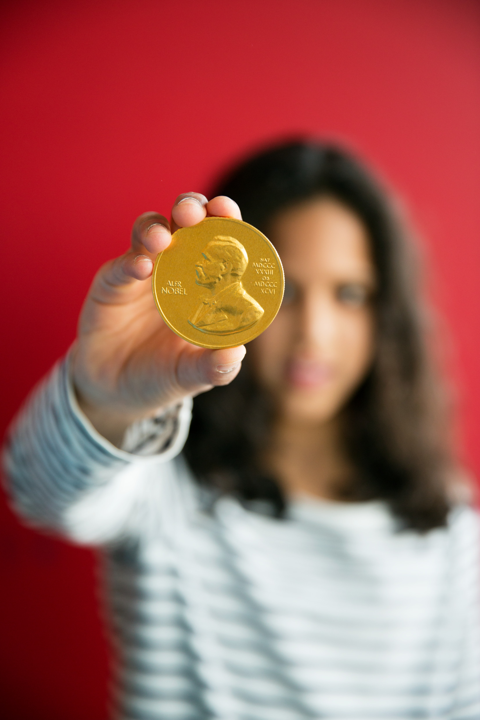 A woman holding a gold medal with Nobel's portrait.