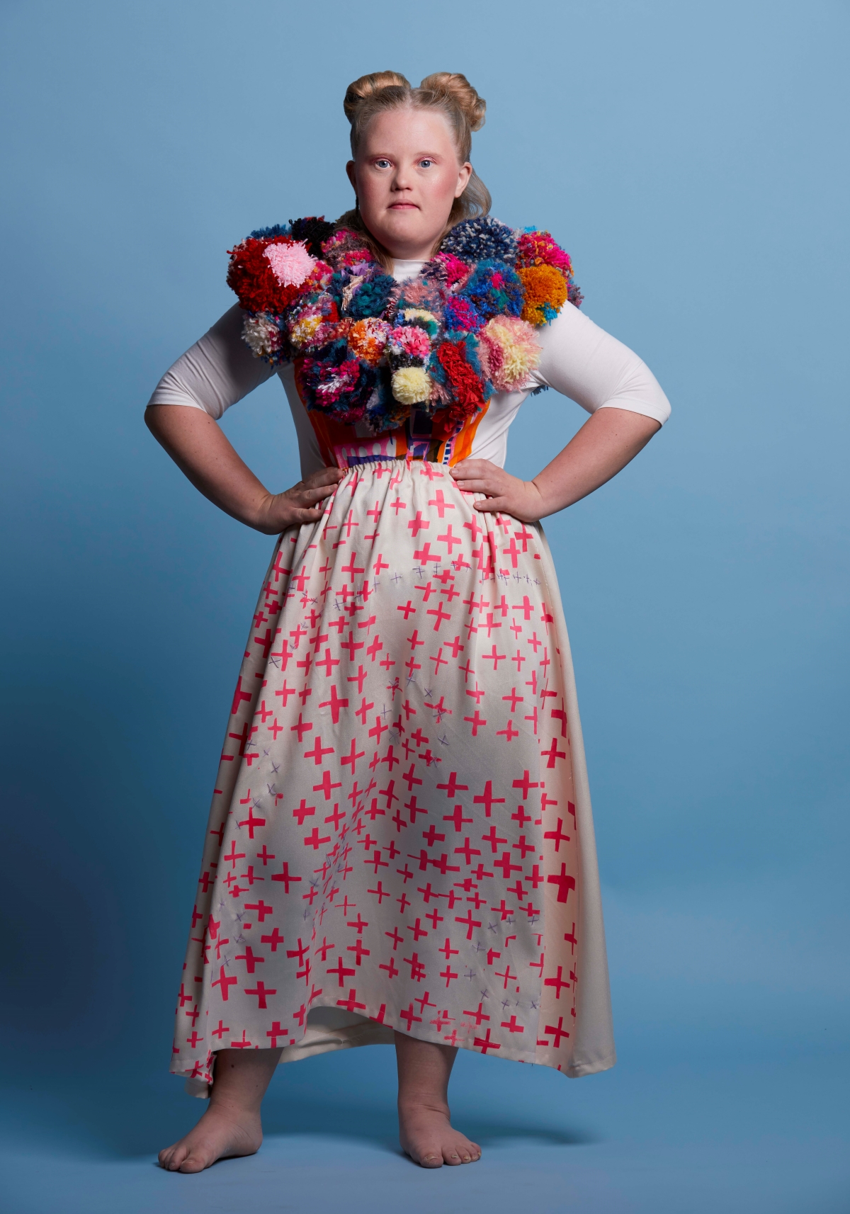 A girl with Downs syndrom with a large pom-pom collar around her neck.