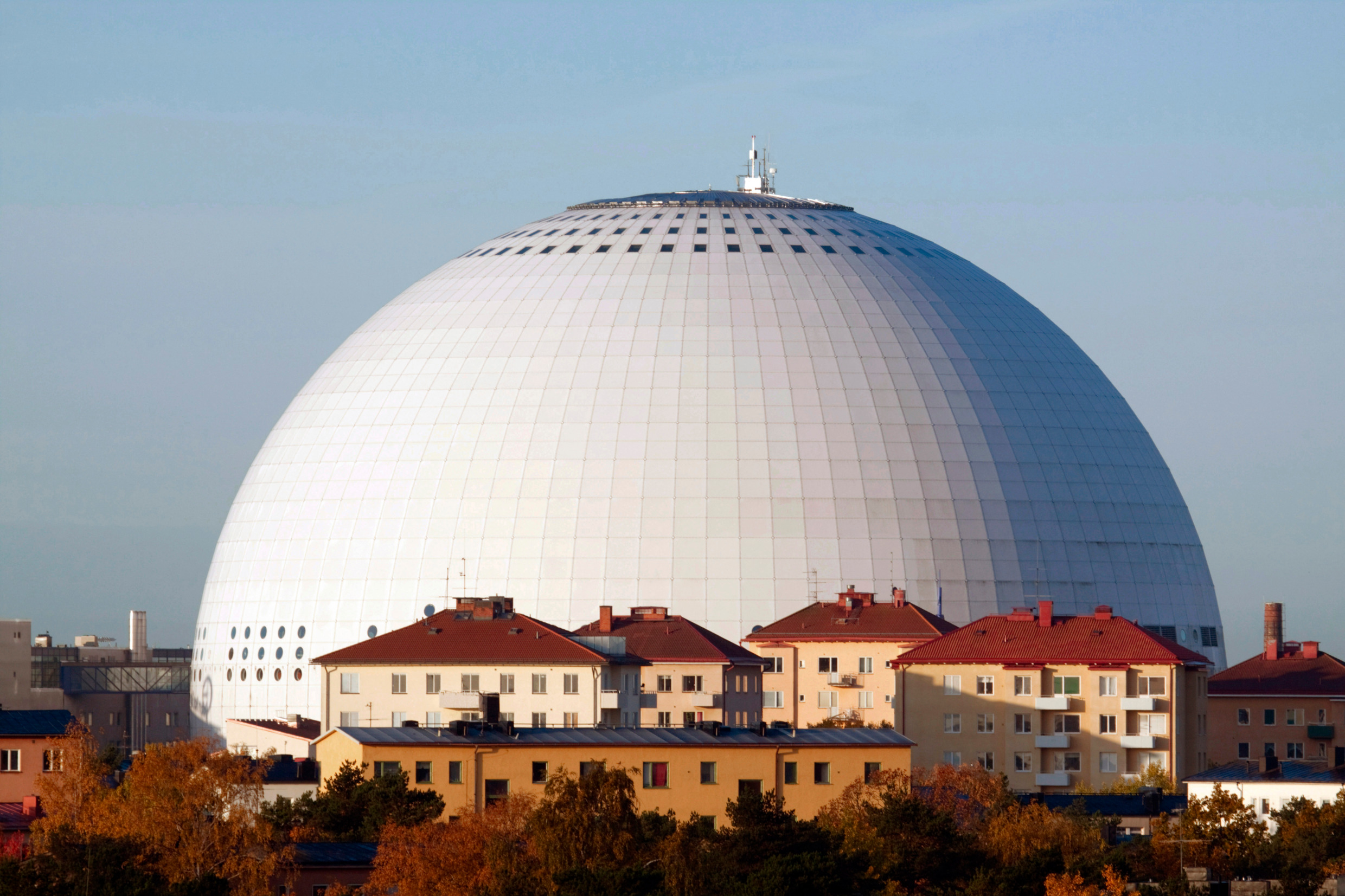The round, white Avicii Arena formerly known as Ericsson Globe with apartment buildings in front of the arena.