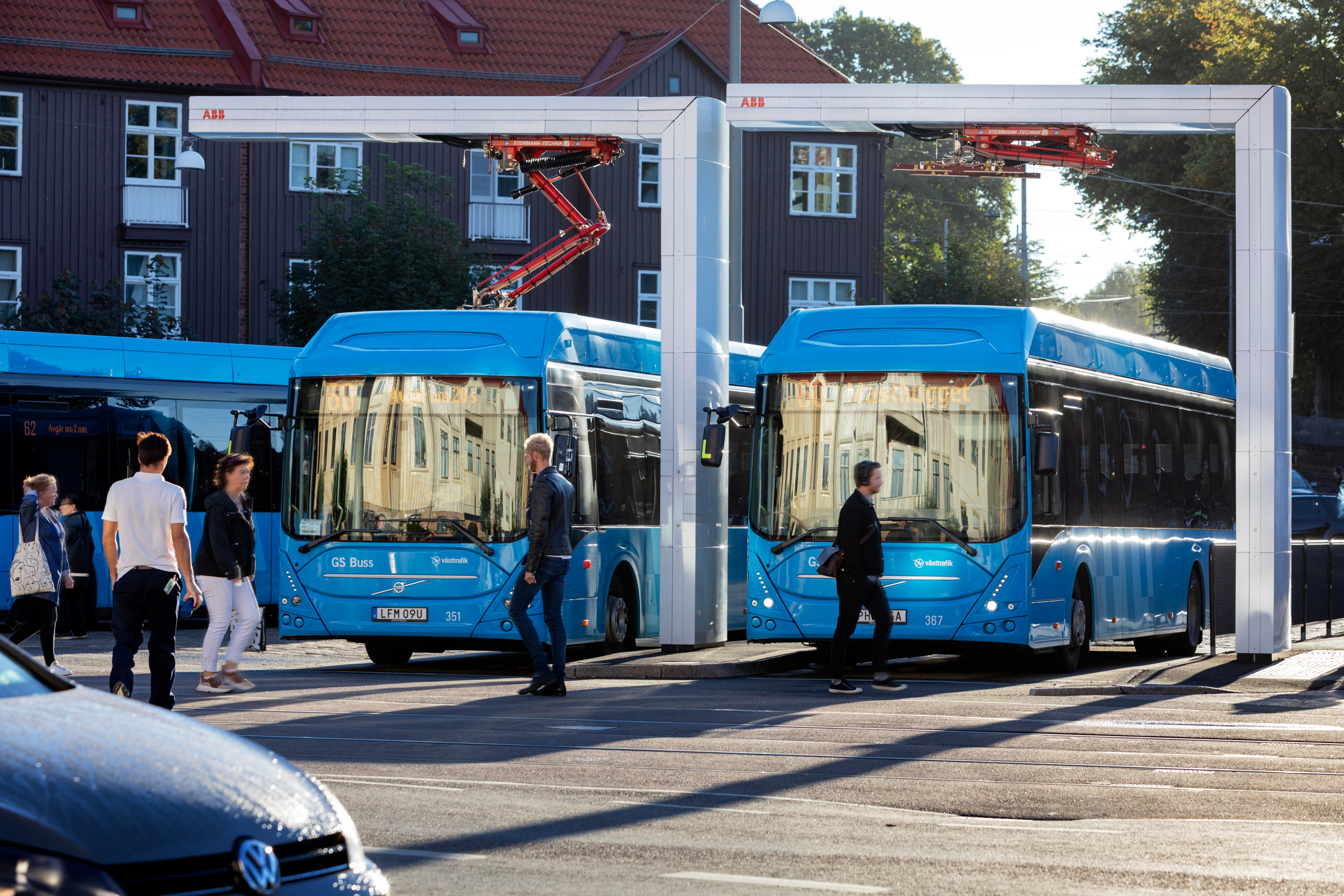 Two buses parked at an electric charging station.
